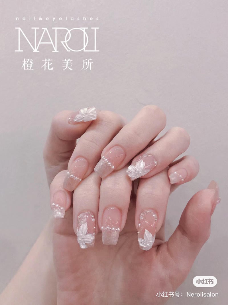 Bàn tay với móng tay được trang trí hoa văn trắng nổi bật trên nền trong suốt.