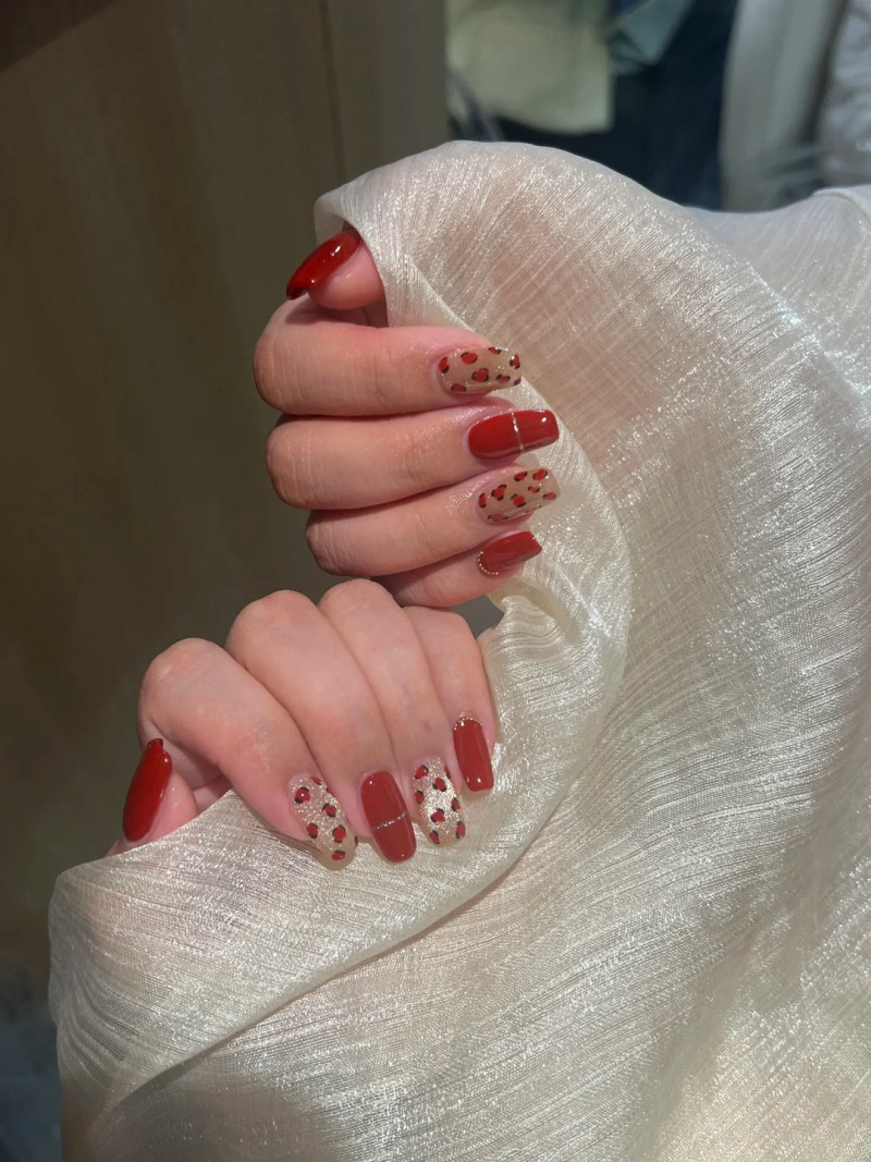 mau-nail-do-trang-cardina-15-jpg_4633ff9378e74c6d9a7fab1999cc0195 Bàn tay cầm vải trắng, móng tay sơn đỏ và họa tiết chấm bi trang trí.