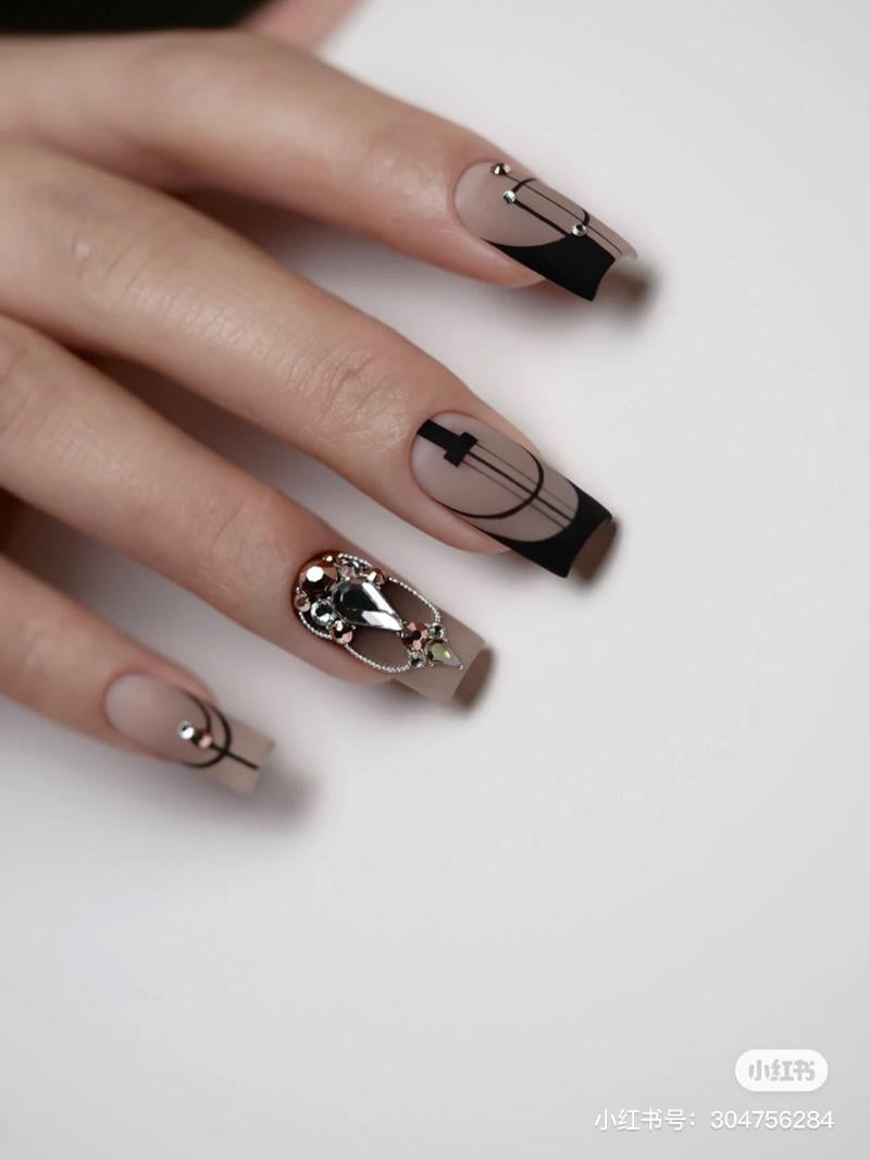 mau-nail-don-gian-cardina__113__c0726fd6699043c88fa5c4902a5ab06f Bàn tay với móng tay được trang trí họa tiết đen trắng và đính đá, tạo kiểu dáng nghệ thuật tinh tế.