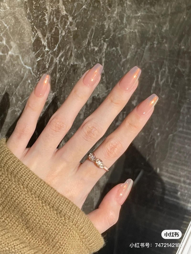 mau-nail-don-gian-cardina__115__6493ad4497c7485ebd11c2051076a912 Bàn tay đeo nhẫn, móng tay dài sơn bóng, trên nền đá cẩm thạch, áo len màu nâu nhạt.