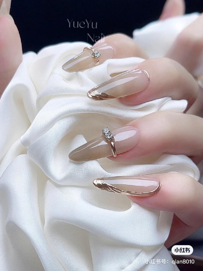 mau-nail-don-gian-cardina__122__da605dc11df045eeb2fde76a774f5bda Bàn tay với móng tay dài, trang trí họa tiết màu vàng, đang cầm vải trắng mềm mại.