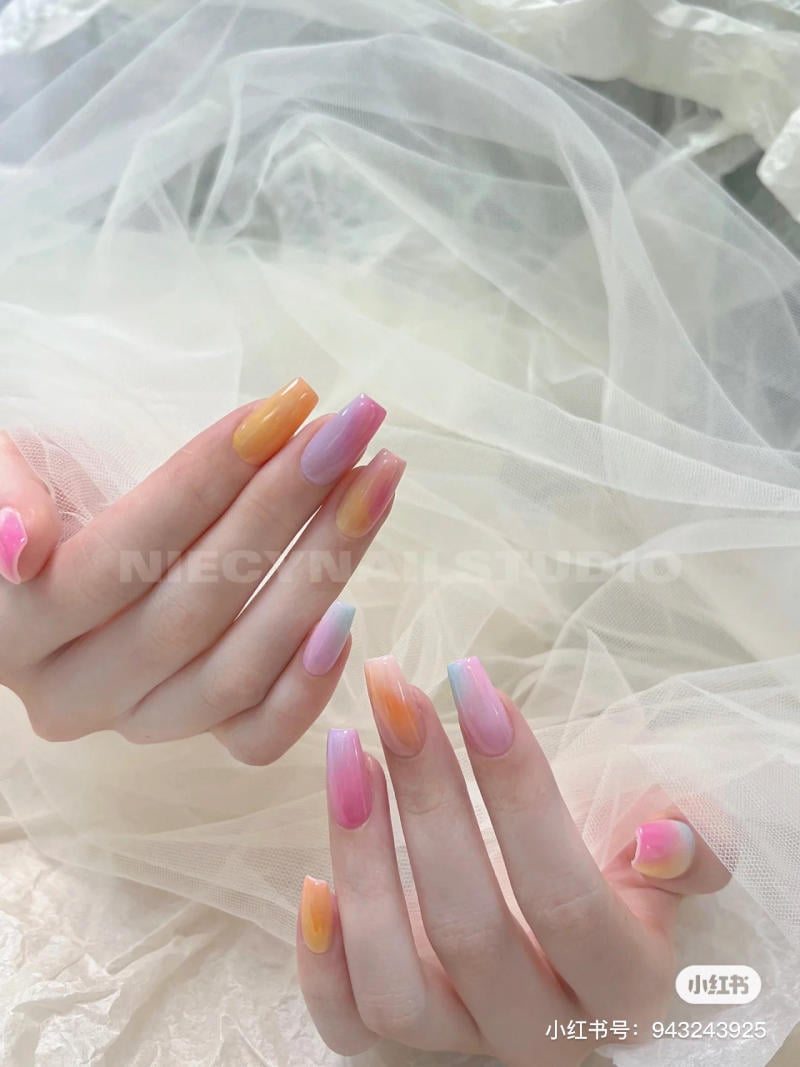mau-nail-don-gian-cardina__125__d378929bc19c4a0ba317d0d225339c2b Các bàn tay với móng tay dài được sơn màu gradient pastel, đặt trên nền vải trắng mềm mại.