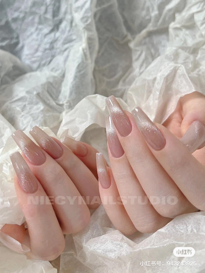 mau-nail-don-gian-cardina__129__55a4128292304b89aad886a98c4b9e03 Bàn tay với móng tay dài được sơn màu hồng nhạt, nổi bật trên nền giấy trắng nhăn.