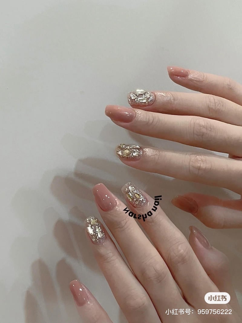 mau-nail-don-gian-cardina__143__b69cd3c8b3f74baa85ad4e31a52f7cac Hai bàn tay với móng tay được sơn màu hồng nhạt và trang trí họa tiết ánh kim lấp lánh.