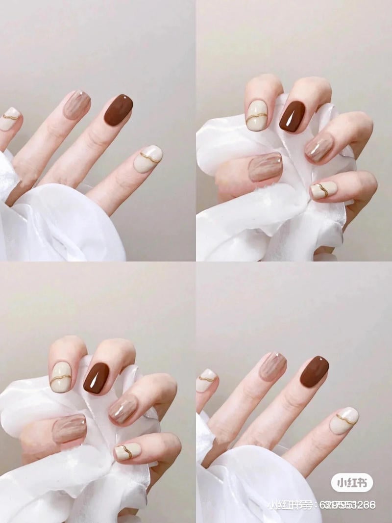 mau-nail-don-gian-cardina__19__2f41493e3a45424d852324019fab3f2a Bàn tay với móng nghệ thuật màu nâu và be, thiết kế đơn giản và thanh lịch, cầm một tấm vải trắng.
