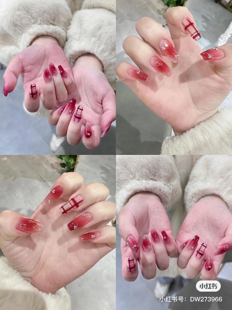 mau-nail-don-gian-cardina__49__a1d8fc0d9439491d9d1383d7d1ca79f4 Bàn tay với móng tay được sơn màu đỏ và trang trí hoa văn, một số móng có đính đá lấp lánh.