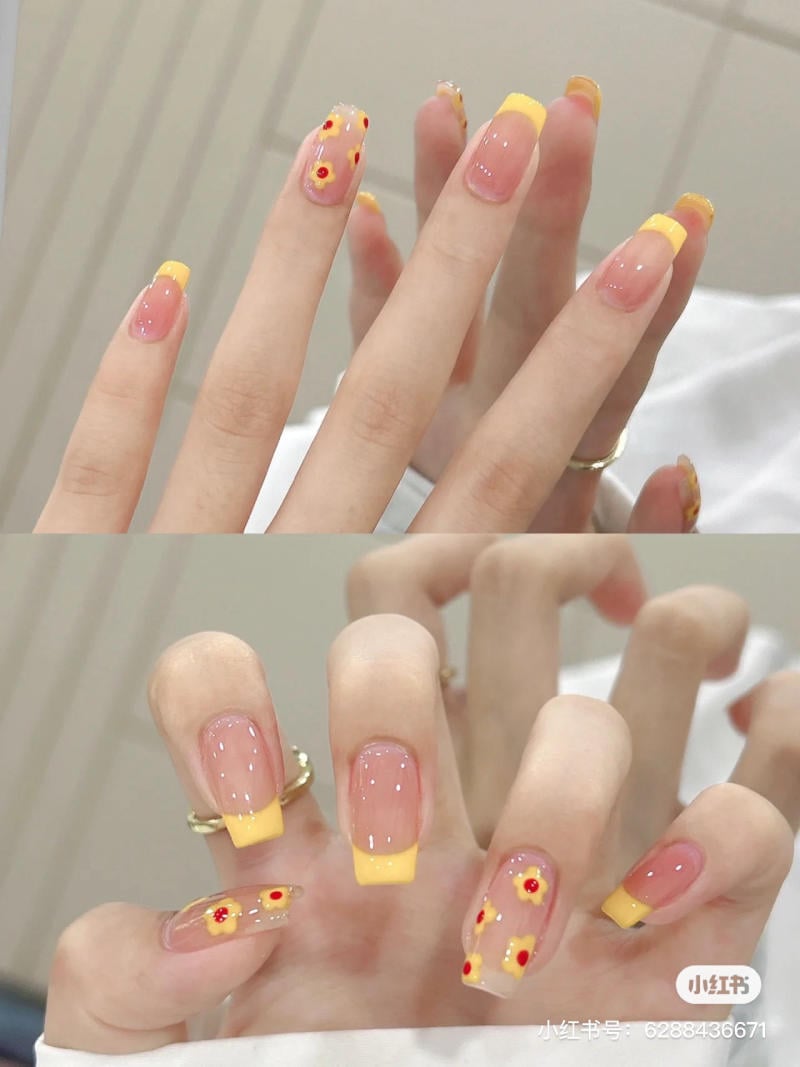 mau-nail-don-gian-cardina__69__906ffc71889245f0bf5277680e3f3ff7 Bàn tay với móng tay sơn kiểu Pháp màu vàng, trang trí họa tiết hoa nhí đỏ và vàng trên nền trong suốt.
