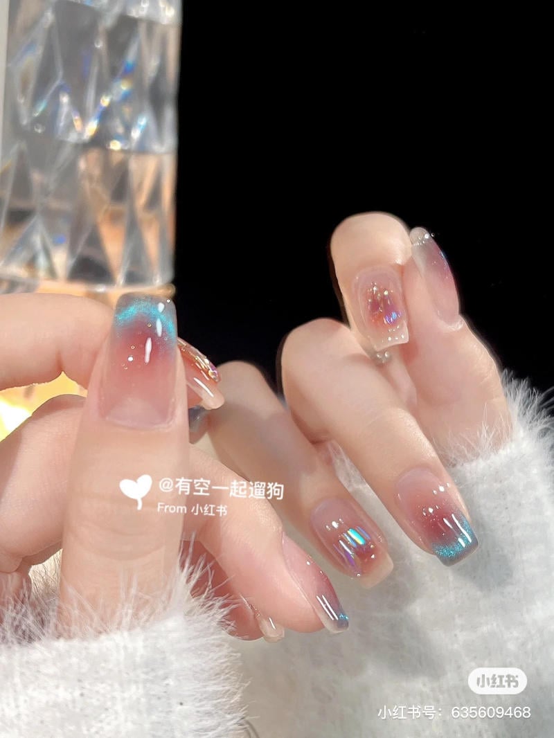 Bàn tay với móng tay được trang trí họa tiết lấp lánh, nền đen, ánh sáng chiếu sáng từ vật thể pha lê.