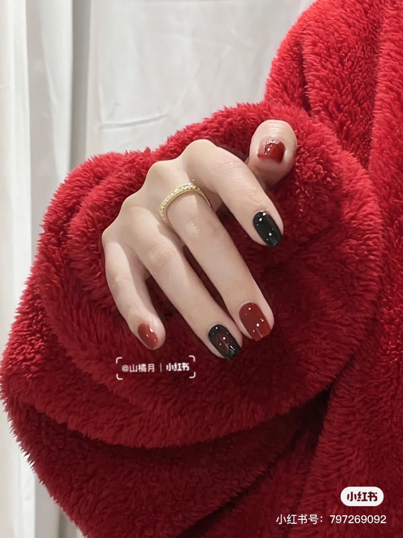 Tay mang áo lông đỏ, móng tay sơn màu đỏ và đen, đeo nhẫn vàng đơn giản.