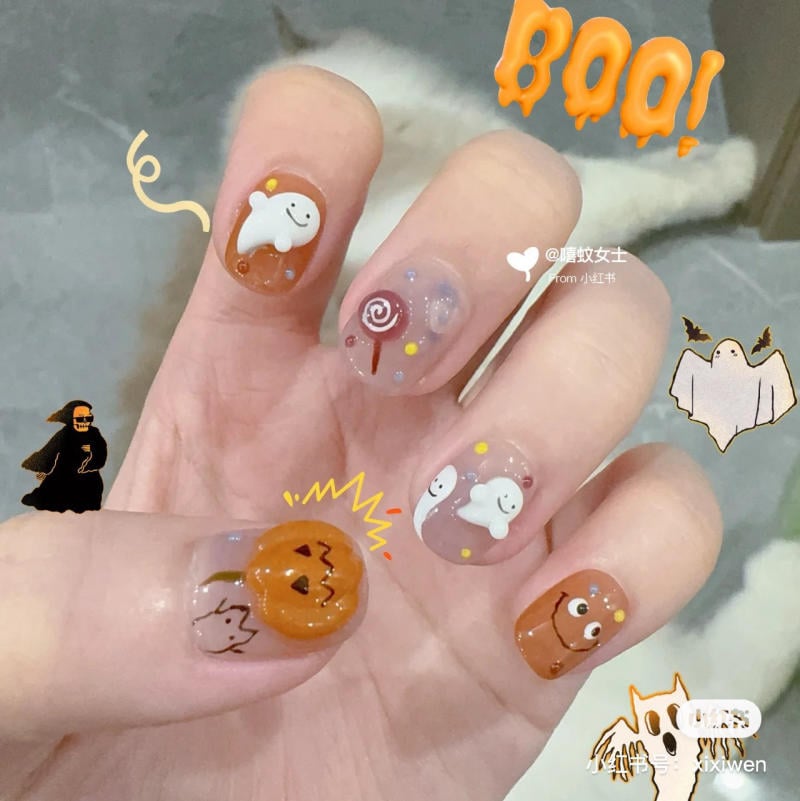 mau-nail-halloween-2023__2__bc4c9b95c0d84da682459d5f55c97e99 Bộ móng tay được trang trí với hình ảnh ma, bí ngô và kẹo, mang phong cách lễ hội Halloween vui nhộn.