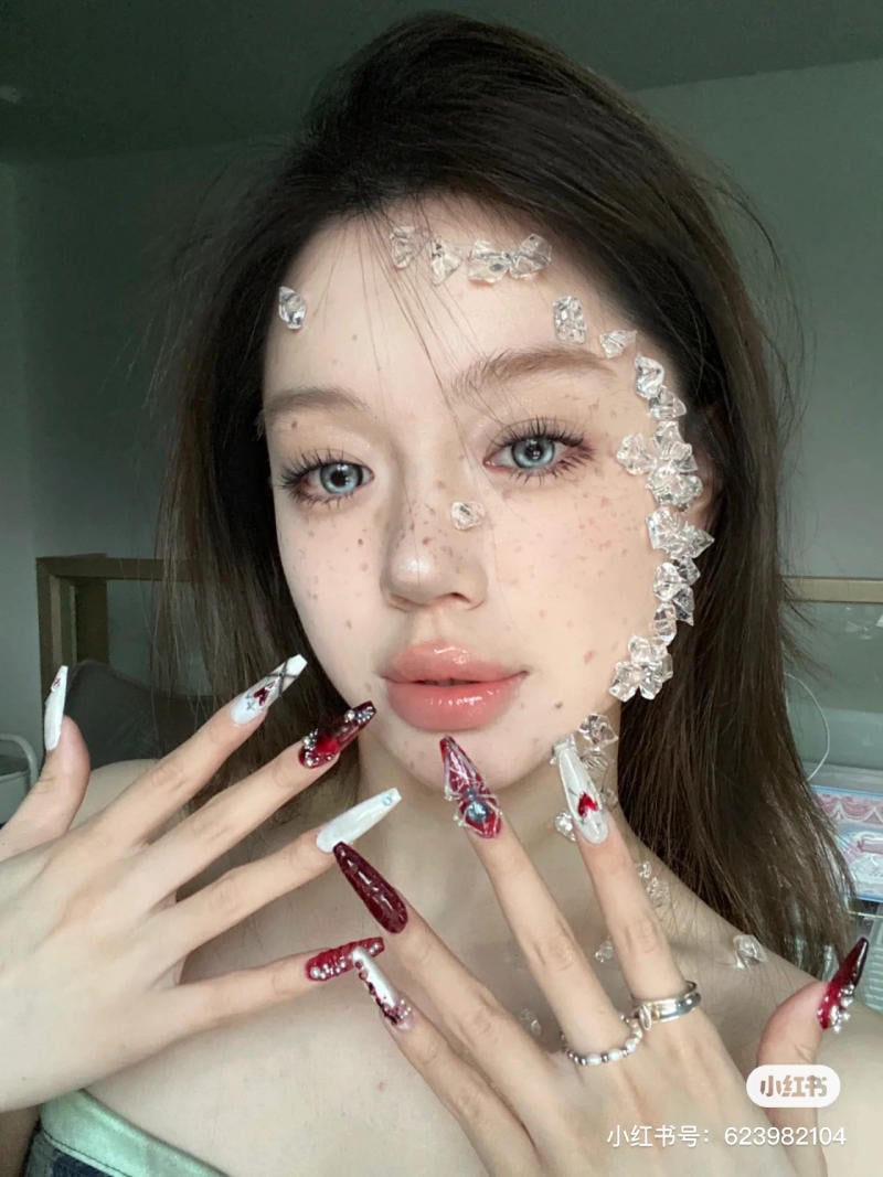 mau-nail-halloween-dep__25__095ecb32f3df410296ea4a179ac87613 Người cầm tay có móng dài được trang trí, đính đá trên mặt, trong không gian nội thất.