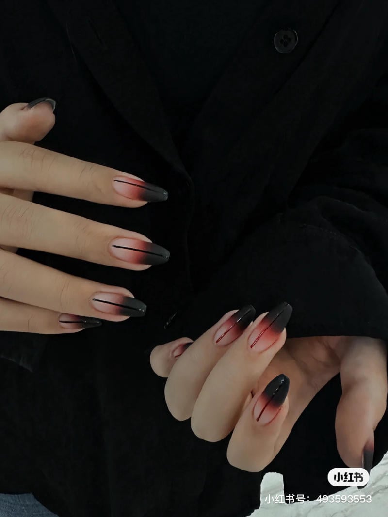 mau-nail-halloween-dep__29__3ee496da29bc4881b6179613e5056d89 Bàn tay với móng tay dài, được sơn màu đỏ đen ombre, trên nền áo đen.