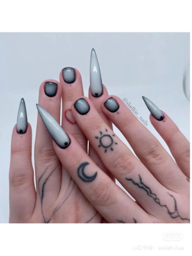 mau-nail-halloween-dep__30__6aaa092d60a943239e9e17fe50a7615a Bàn tay với móng tay nhọn màu xám ombre, có hình xăm mặt trời, mặt trăng và các đường nét trên ngón tay.