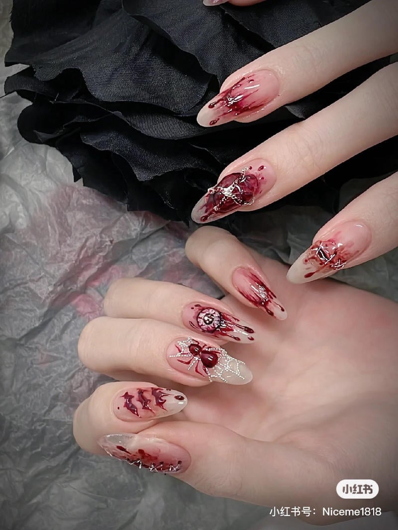 mau-nail-halloween-dep__49__5a9753d7ec554497b5272e456d445717 Bàn tay với móng tay nghệ thuật, họa tiết màu đỏ và đen, nền vải tối màu.