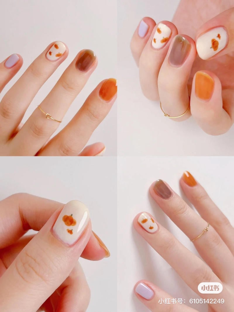 mau-nail-halloween-dep__50__577e61f00b3e40f499f51e88b633beaf Bàn tay với móng tay trang trí họa tiết hoa bí ngô, sơn màu pastel và nâu, đeo nhẫn mảnh trên ngón tay.
