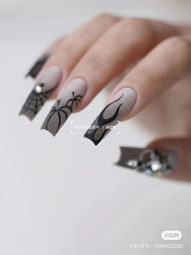 mau-nail-halloween-dep__60__6059477828084b6e90708738a0652bbb Bàn tay với móng tay dài, trang trí hoa văn mạng nhện và họa tiết đen trên nền màu xám.