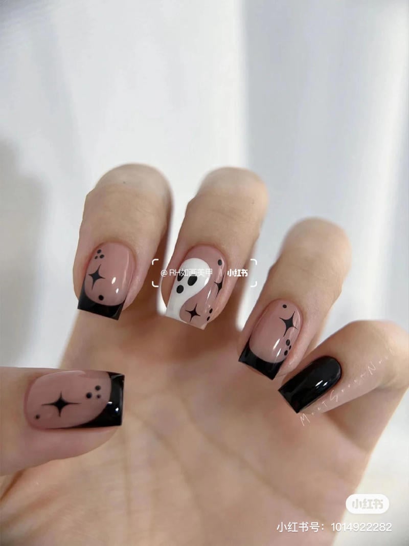 mau-nail-halloween-dep__61__31293a35a44f45169be6a45b21a54751 Bàn tay với móng tay được sơn màu đen và hồng nhạt, có họa tiết trừu tượng trên nền sáng.