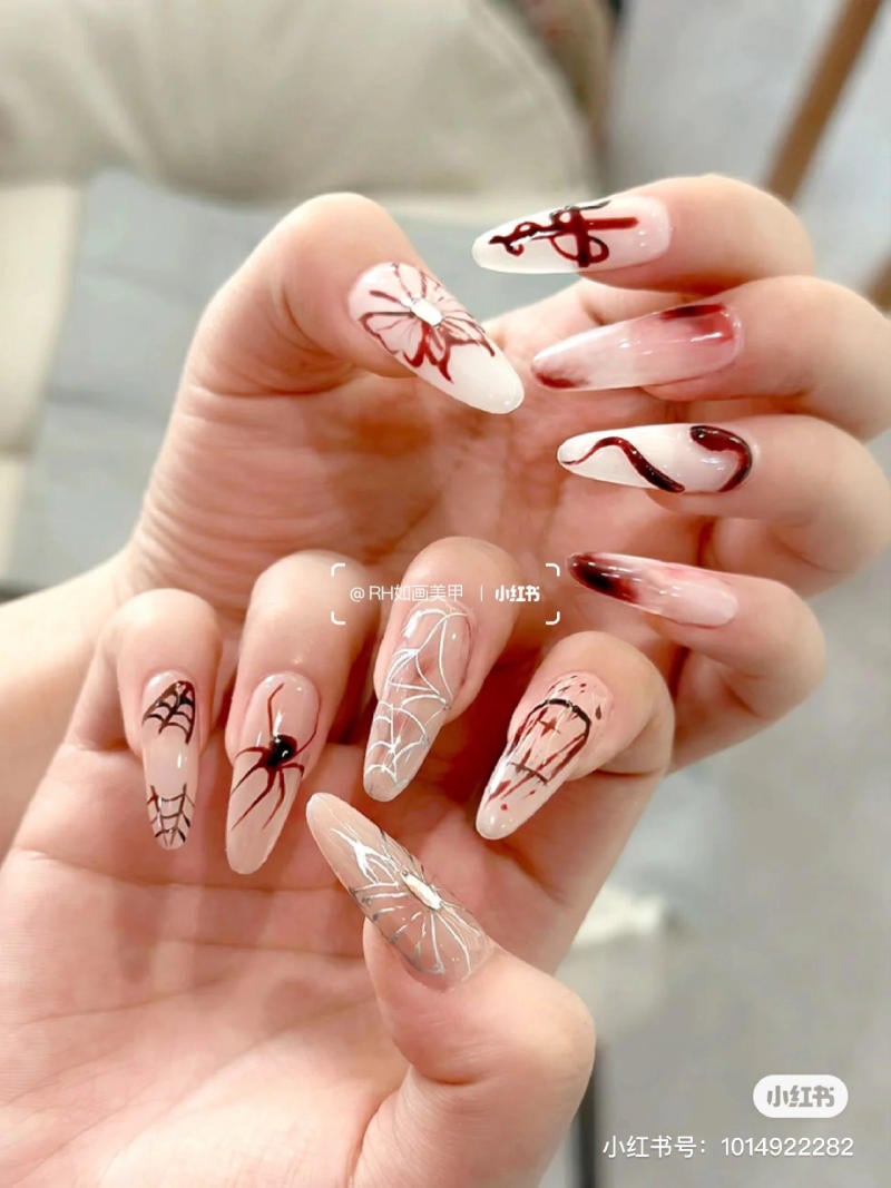 mau-nail-halloween-dep__65__153338a64185408aaf662d32133c8cef Bàn tay với móng tay dài được trang trí họa tiết hoa và mạng nhện, tông màu đỏ, trắng và đen.