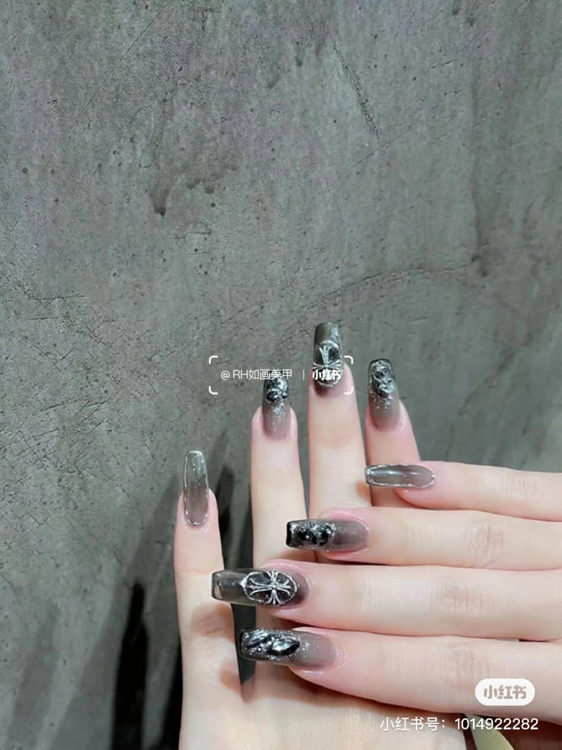 mau-nail-halloween-dep__66__da17f3a6ec2542dcad66631d5856b0d1 Bàn tay với móng tay được trang trí nghệ thuật màu đen và xám, nền là bề mặt tường xám.