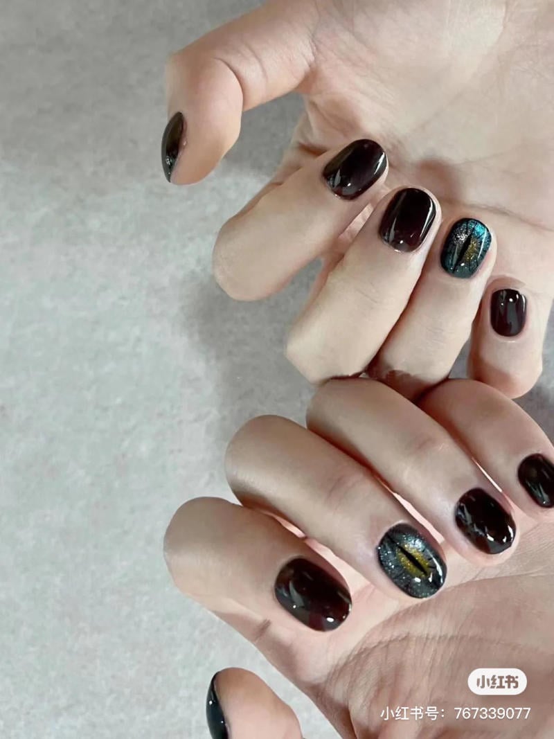 mau-nail-halloween-dep__70__8c56e6bc820549659f072dce0aa381a8 Bàn tay với móng tay sơn màu đen, có một móng trang trí họa tiết lấp lánh.