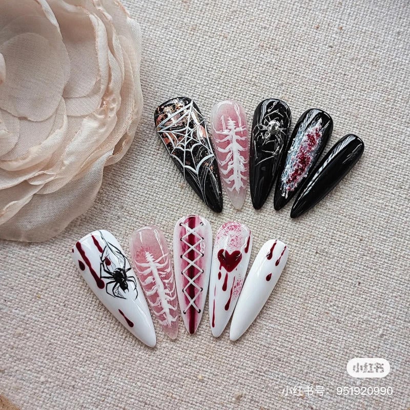 mau-nail-halloween-dep__7__f869d914bccf4c95b088fc3f27b46a88 Bộ móng giả với họa tiết mạng nhện, xương, máu và tim, được thiết kế trên nền đen, trắng và hồng.
