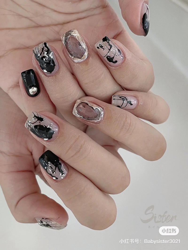 mau-nail-halloween-dep__9__f6768ce3ed7e4d79a9bb04aa91664bc8 Bàn tay với móng tay được trang trí nghệ thuật, sơn màu đen và bạc kết hợp họa tiết trừu tượng.