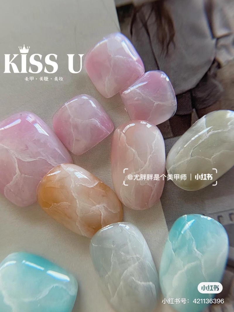 Bộ móng giả với nhiều màu sắc như hồng, xanh và cam, bề mặt bóng và có vân đá tự nhiên.