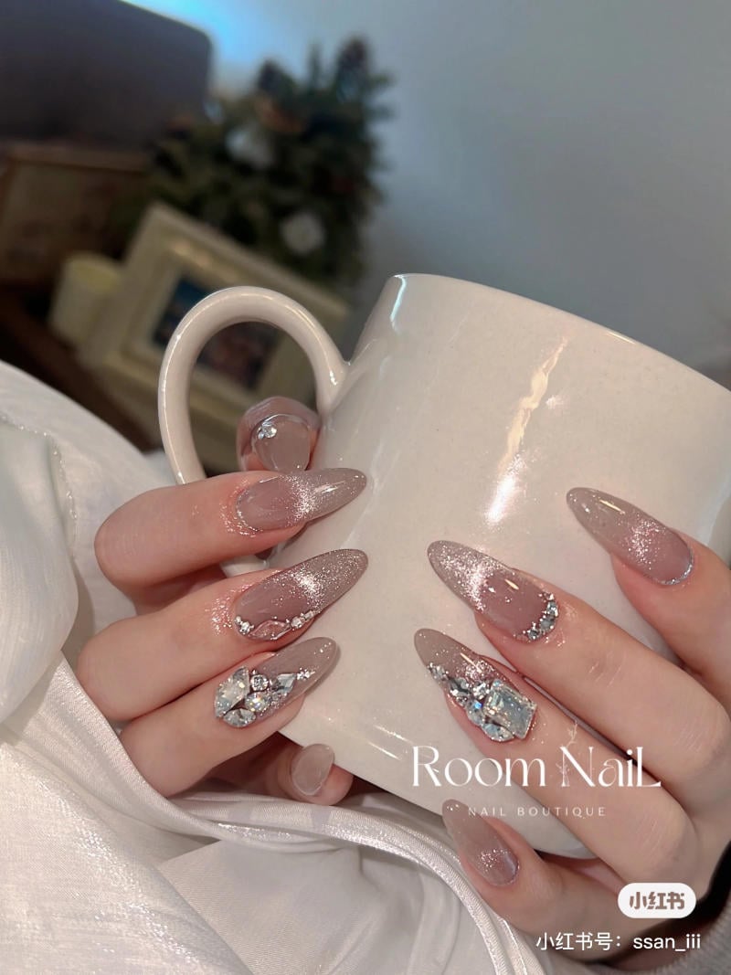Một đôi tay cầm cốc trắng, móng tay dài được trang trí lấp lánh với đá quý.