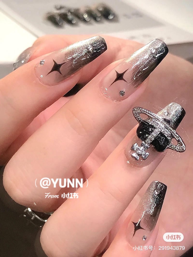 Bộ móng tay thiết kế tông màu bạc đen với họa tiết ngôi sao và phụ kiện trang trí nổi bật trên ngón tay.