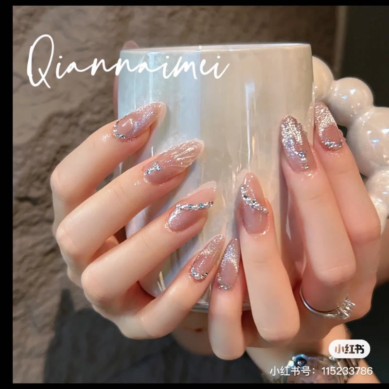 Bàn tay với móng tay được trang trí họa tiết lấp lánh, cầm một chiếc cốc màu trắng bóng.