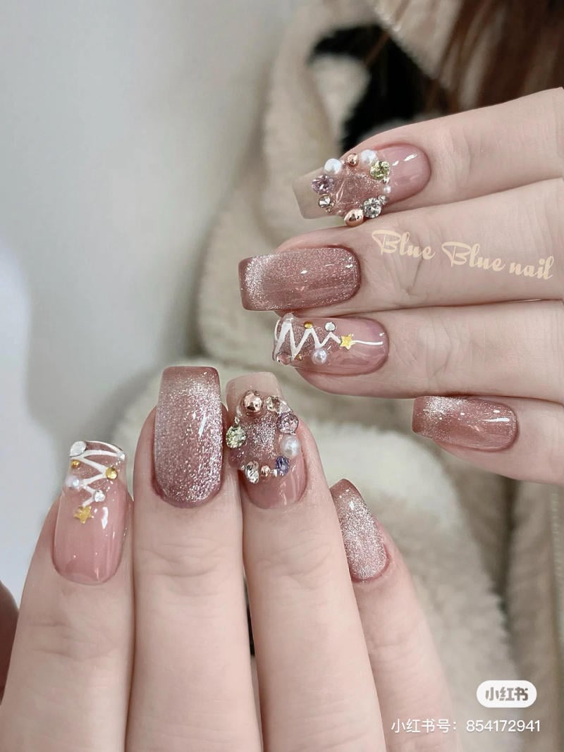 Bộ móng tay được trang trí với sơn màu nâu hồng, đính đá và họa tiết trang trí nổi bật.