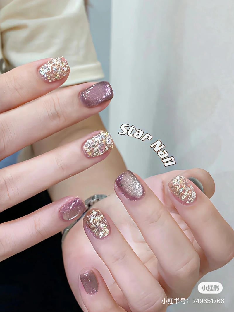 Bàn tay với móng tay được sơn màu tím và phủ kim tuyến sáng bóng, tạo hiệu ứng lấp lánh.