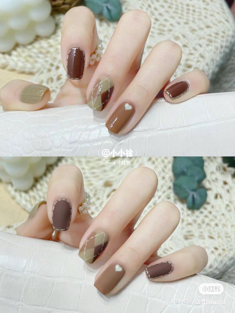 Bàn tay với móng tay được sơn họa tiết caro và màu nâu, có hình trái tim nhỏ trên một ngón.