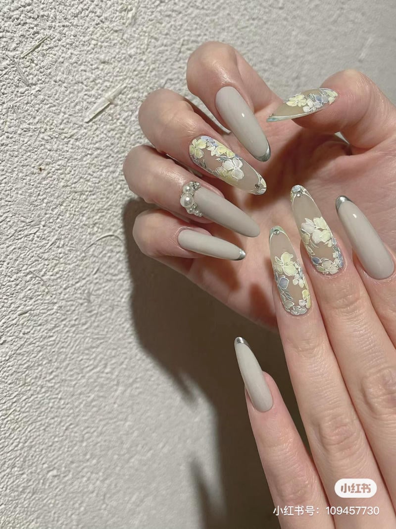 mau-nail-mong-nhon-dai__14__2b870d2954b048c4bf057515db3750b3 Bàn tay với móng tay dài, trang trí hoa và màu sơn trung tính.