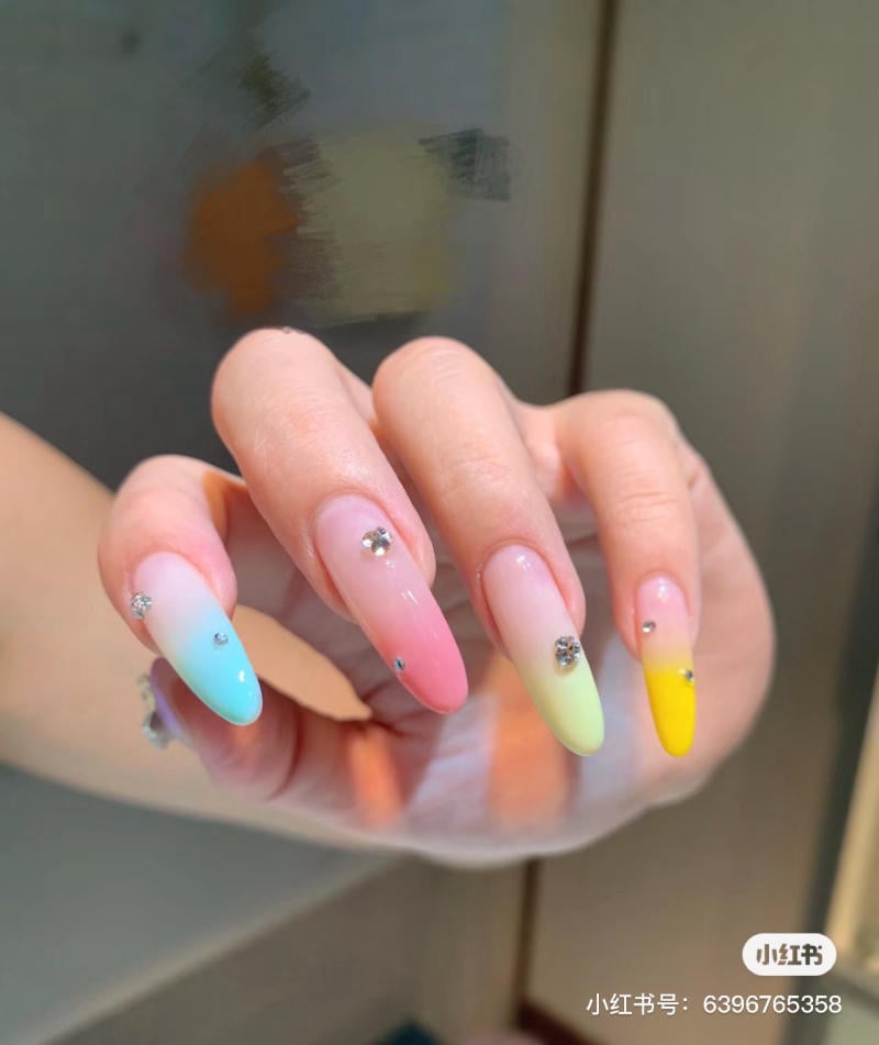 mau-nail-mong-nhon-dai__8__389e451c0372452ba29f1e8d1992827d Bàn tay với móng tay dài được sơn màu ombre pastel và trang trí đá nhỏ.