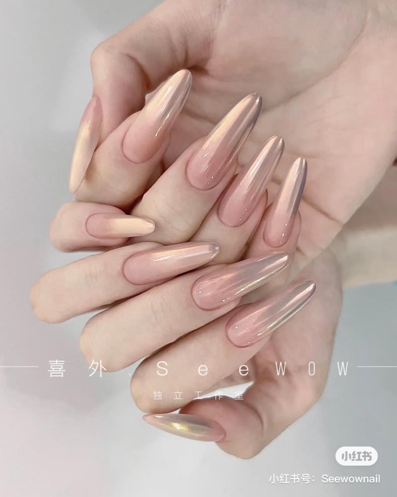 mau-nail-mong-nhon-tron__13__d6ff31bd2b8e4c1a86fad74518f9be2c Bàn tay với móng dài, được sơn màu ombre hồng nhạt bóng, trên nền phông trắng đơn giản.