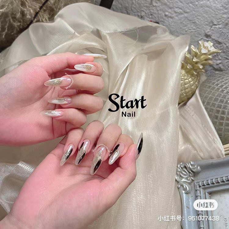 mau-nail-mong-nhon-tron__3__1e79f6febd714f6fae00dc0c2cdbfdbd Hai bàn tay với móng tay được trang trí nghệ thuật, nền vải sáng màu và chi tiết trang trí kim loại.