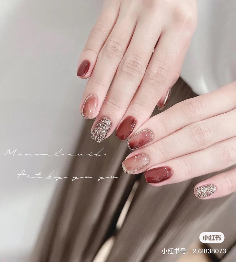 Bàn tay với móng tay được sơn màu đỏ và ánh nhũ, kiểu dáng trang trí nghệ thuật tinh tế.