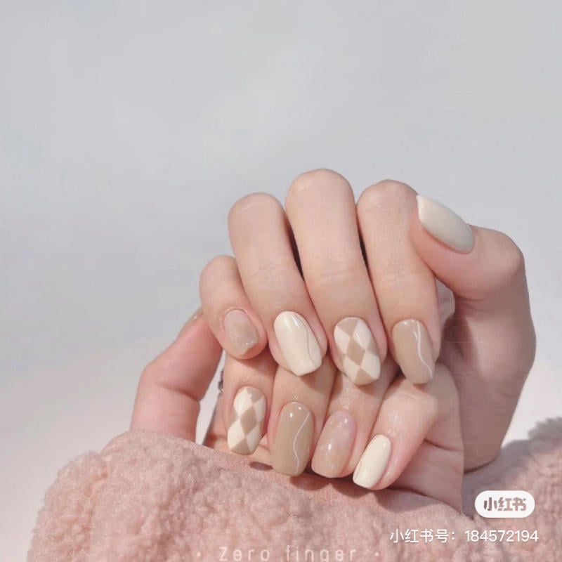 Bàn tay với móng tay được sơn màu nude và họa tiết hình học tinh tế.