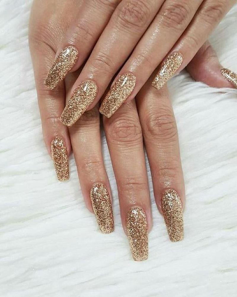 mau-nail-nhu-dep__19__1f6926f490d34c5aa3d5b5f20ccece2b Bàn tay với móng tay dài được sơn màu vàng lấp lánh, nằm trên nền vải trắng.