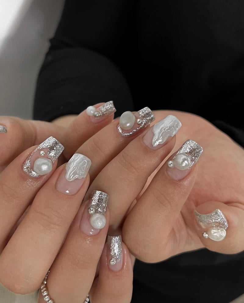 mau-nail-nhu-dep__45__535ed403dba84bc4b00a86a5f72bdfe8 Bàn tay với móng giả trang trí bạc, trắng và ngọc trai.