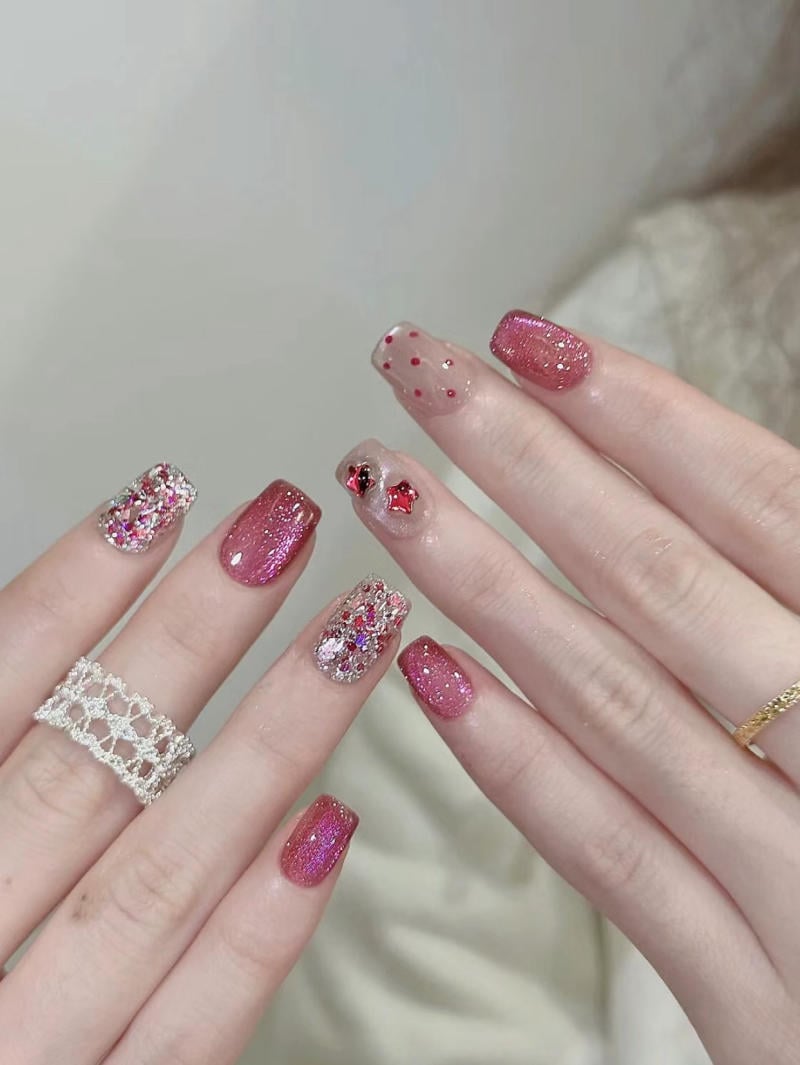 mau-nail-nhu-dep__54__834c8051c5a843be9ddee64e070bd3a4 Móng tay được sơn màu hồng lấp lánh, một số ngón có trang trí hoa văn chấm bi và đính đá.