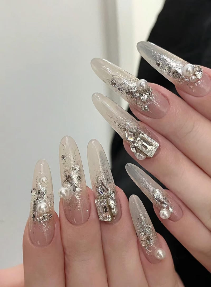mau-nail-nhu-dep__60__0e592b225a8d417081575b049c44946b Bộ móng tay dài, trang trí đá và ngọc trai trên nền màu hồng nhạt, tạo điểm nhấn lấp lánh.