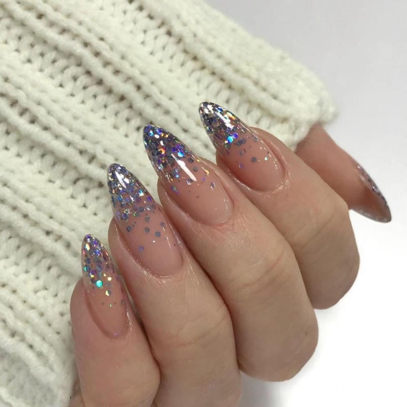 mau-nail-nhu-dep__9__244258b4095f484e8ea6deb2a84ac524 Bàn tay với móng tay dài, sơn màu nude và lấp lánh ánh kim, đặt trên nền áo len trắng.