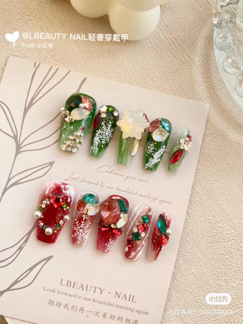 mau-nail-noel-dep__1__9a9292909bd44cfbb1c30da1c7fafb49 Bộ móng giả trang trí giáng sinh với màu xanh, đỏ và họa tiết bông tuyết, đá quý trên nền giấy trắng.