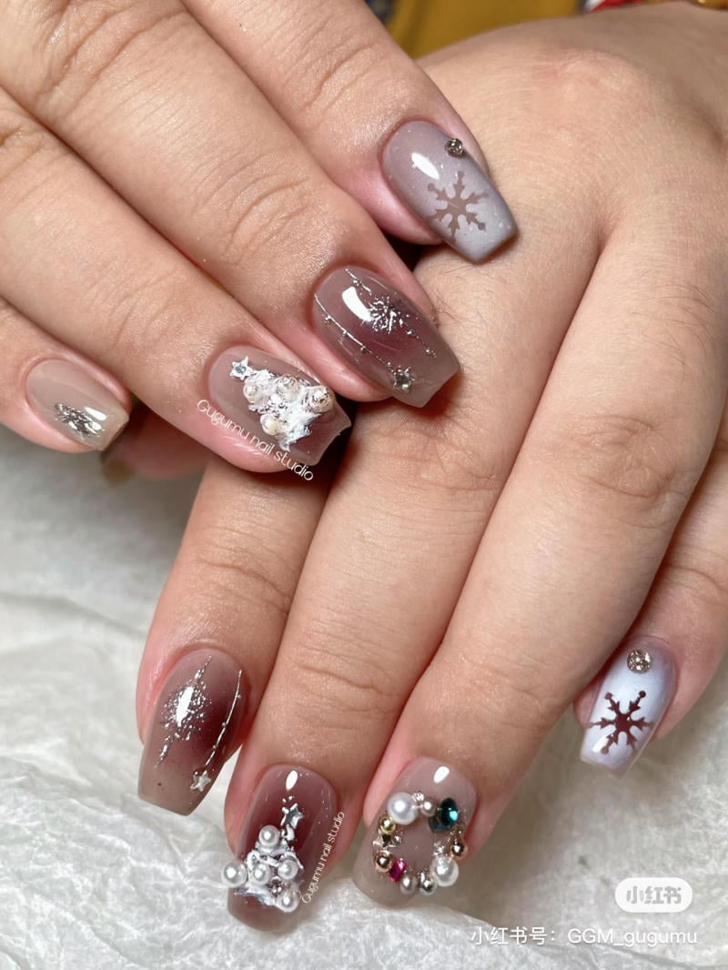 mau-nail-noel-dep__21__3deaf4eb87cc4b7ba9a1030f568ef1eb Bộ móng tay trang trí tinh tế với họa tiết bông tuyết và ngọc trai trên nền màu nâu và xám.