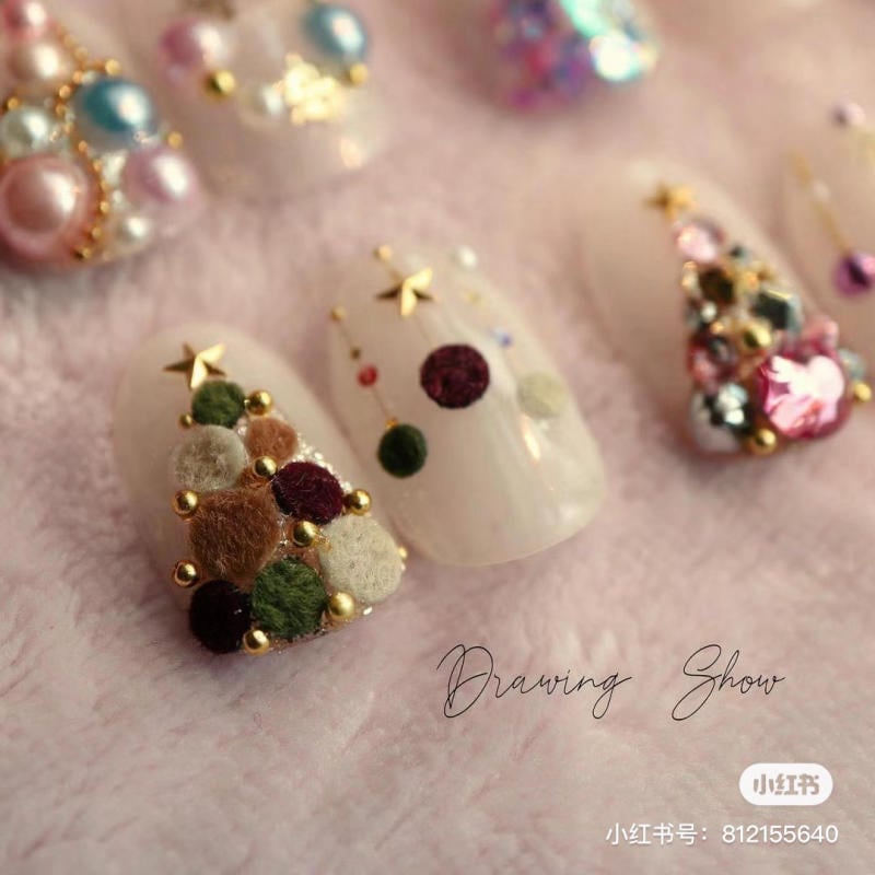 mau-nail-noel-dep__25__7728901755d149c489f4de365d1a6a99 Mẫu móng tay trang trí với hạt cườm và ngôi sao trên nền màu trắng, chụp trên nền vải mềm mại.