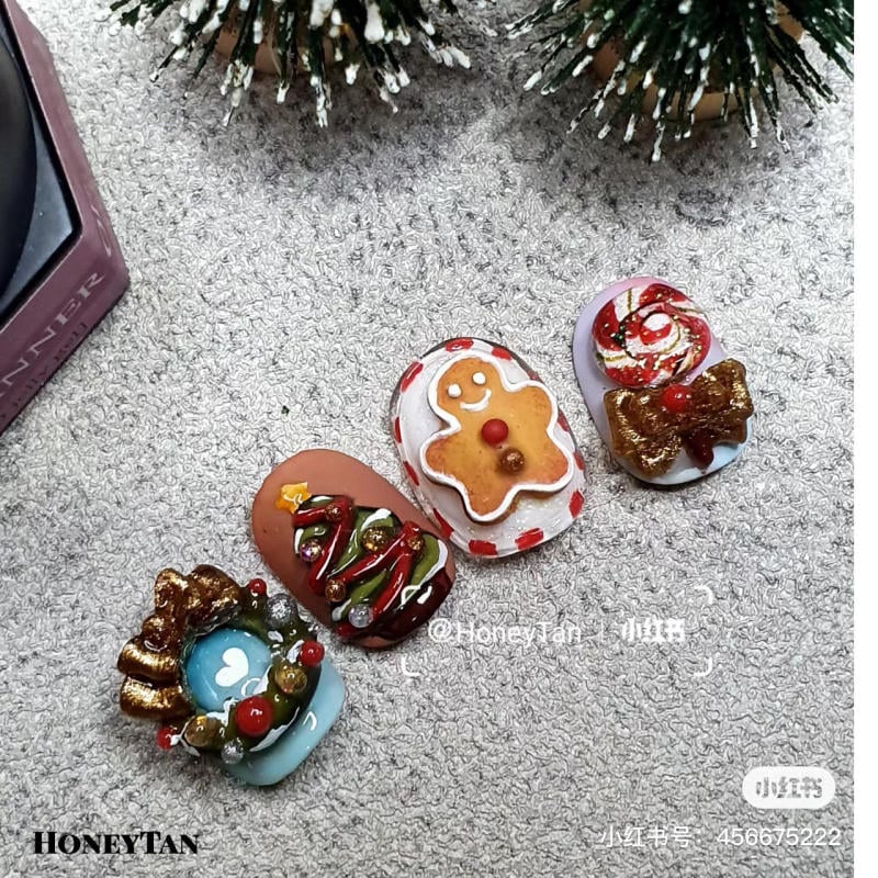 mau-nail-noel-dep__28__df1c1914bf79497aba284b72942f1e54 Bộ móng tay giả trang trí Giáng sinh với hình bánh gừng, kẹo, vòng hoa và cây thông trên nền vải xám.