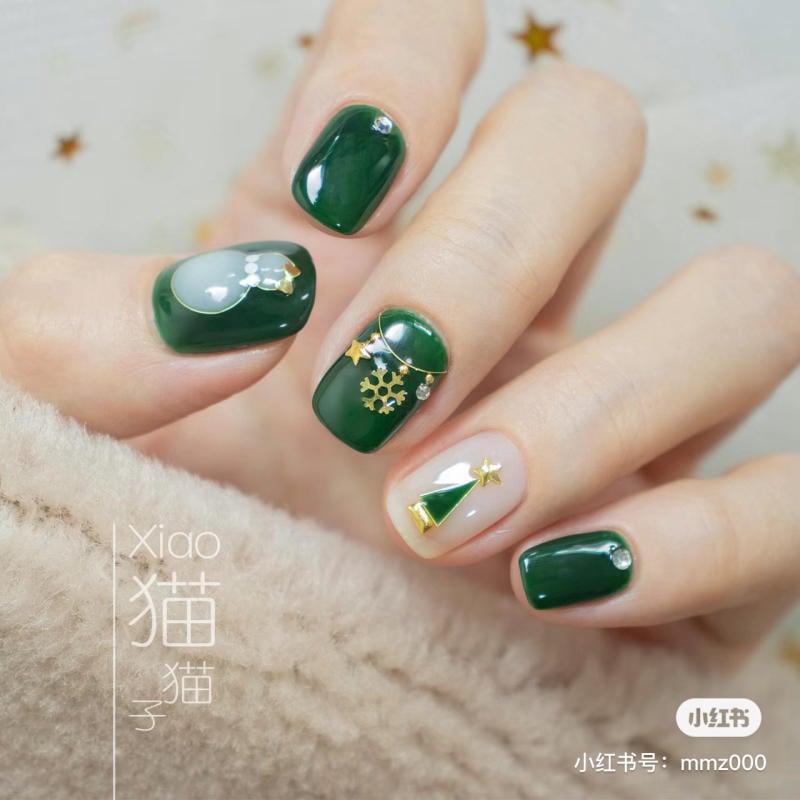 mau-nail-noel-dep__29__38e994b1d6284c92abf2cf69ef48b729 Bộ móng tay trang trí màu xanh lá cây với họa tiết cây thông và bông tuyết trên nền màu trắng và xanh.