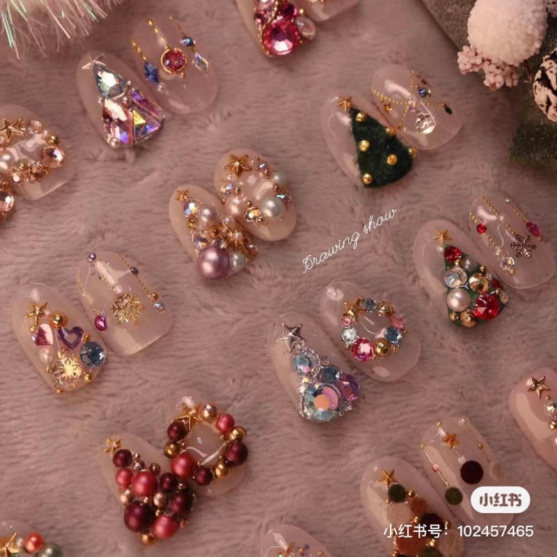 mau-nail-noel-dep__36__572fad99bda24c98bf80c600c2f26b11 Mẫu móng tay nghệ thuật với trang trí đá quý và họa tiết Noel trên nền màu hồng nhạt.